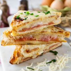 three sandwiches stacked on top of each other with cheese and meat in the middle next to eggs