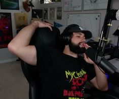 a man with headphones sitting in a chair next to a microphone and recording equipment