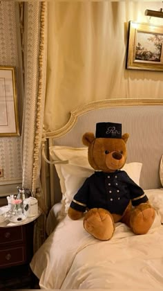 a teddy bear sitting on top of a bed in a room with white sheets and pillows