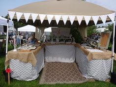 an outdoor tent set up on the grass with tables and chairs under it for sale