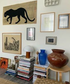 there are many pictures on the wall and vases in this room, including one with a black cat