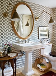 a white sink sitting under a bathroom mirror next to a black and white wallpaper