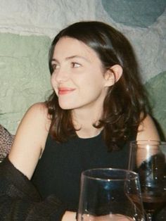 two women sitting next to each other at a table with wine glasses in front of them