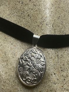 a black velvet cord with a silver pendant on it's end, resting on a marble surface