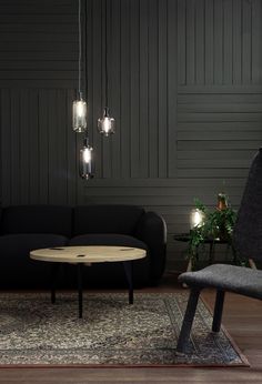 a living room filled with furniture and lights hanging from the ceiling next to a black couch