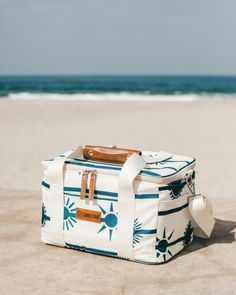 a white and blue bag sitting on top of a sandy beach