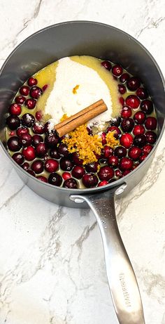 a pan filled with cranberries and spices on top of a marble countertop