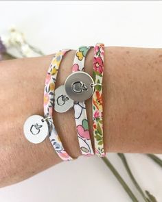 a woman's arm with three bracelets on it and two charms attached to the wrist