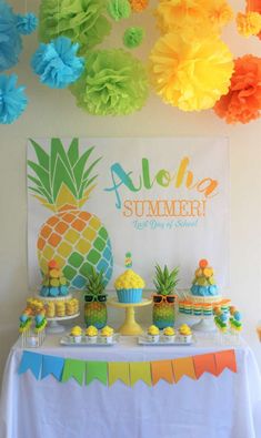 a table topped with cupcakes and cakes next to a sign that says aloha summer