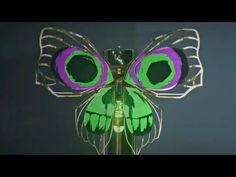 a green and purple butterfly with big eyes on it's wings is seen in this image