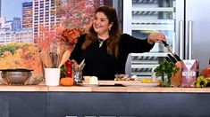 a woman standing in front of a kitchen counter with vegetables and fruit on the counter