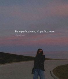 a woman standing on the side of a road next to the ocean with a quote above her that reads, be imperfectedly real it's perfectly rare