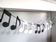 a string of musical notes hanging from the ceiling next to a wall with white and black music notes on it