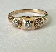 "a most wonderful vintage 14k gold ring with three diamonds, two flowers, and two golds.  this was intended as an engagement ring and likely made in the thirties or forties.  it had one chipped diamond which my jeweler did a beautiful job of replacing and it's looking pretty great for its age.  the central diamond is quite bright and is framed in a bit of white gold, as are the smaller ones.  i LOVE the flower designs around the smaller stones.  ring is marked Fidelity for the maker and 14k with 90s Engagement Ring, Ring With Three Diamonds, Random Numbers, Diamond Trilogy Ring, Vintage Gold Engagement Rings, Two Flowers, Future Engagement Rings, Trilogy Ring, Fashion Moments