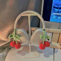 two cherries are attached to the back of an earpiece on a stand in front of a computer screen