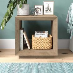 a small wooden shelf with books and pictures on it next to a potted plant