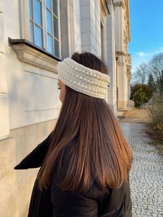 a woman with long hair wearing a headband on her head is standing in front of a building