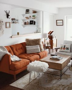 a living room with an orange couch and coffee table in front of a large window