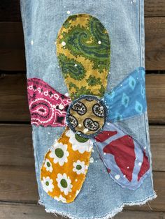 an old pair of jeans has been decorated with fabric flowers and beads on it,