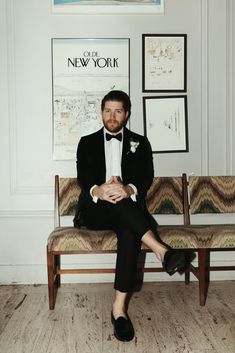 a man in a tuxedo sitting on a bench with his legs crossed and feet crossed