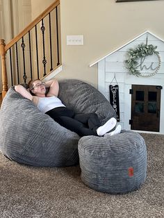 a woman laying on a bean bag chair in a living room next to a stair case