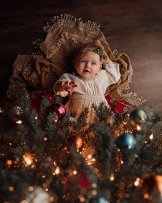 a baby laying on top of a christmas tree