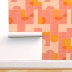 an orange and pink wallpaper with geometric shapes on the wall next to a roll of toilet paper