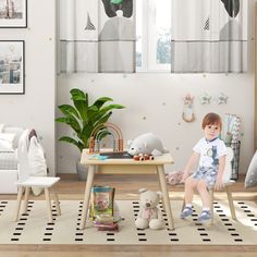 a little boy sitting on top of a wooden table next to a teddy bear toy