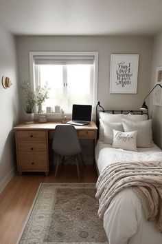 a bedroom with a bed, desk and computer on it in front of a window