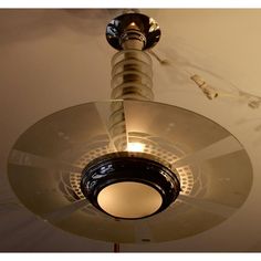 a ceiling fan that is on top of a light fixture in a room with white walls