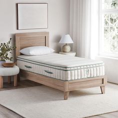 a bed with a wooden headboard and foot board in a room next to a window