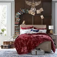 a bed with a red comforter and pillows in front of a bookshelf