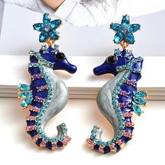 a pair of seahorse earrings with blue and pink crystals on it's sides