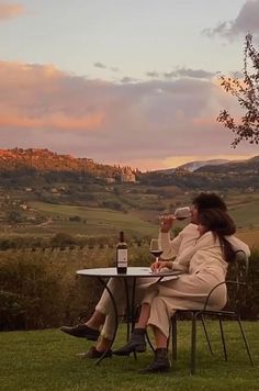 a woman sitting at a table drinking wine