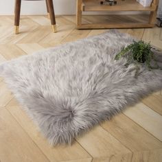 a rug that is laying on the floor next to a chair and table with a plant in it