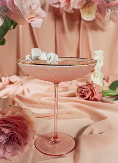 a close up of a wine glass with flowers in the background