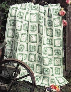 a green and white blanket sitting on top of a wooden bench next to a wheel