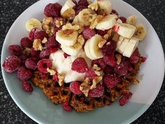 a white plate topped with granola, raspberries and bananas on top of it