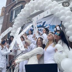 several women in white outfits are posing for a photo with balloons and confetti