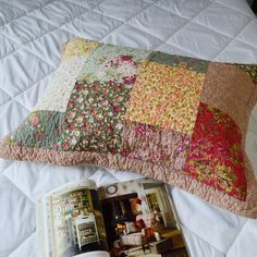 an open magazine laying on top of a bed next to a pillow and coverlet