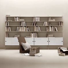 a living room filled with furniture and bookshelves next to a wall mounted book shelf