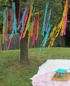 a picnic blanket with colorful streamers hanging from it's sides in the yard