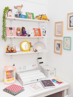 a white desk topped with lots of shelves filled with pictures and toys next to a printer