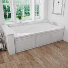 a large white bath tub sitting next to two windows in a room with wooden floors