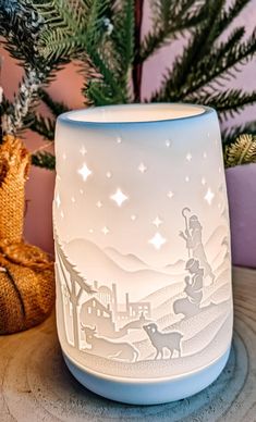 a lit candle holder sitting on top of a wooden table next to a christmas tree