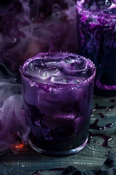 a purple drink sitting on top of a table next to two glasses filled with liquid