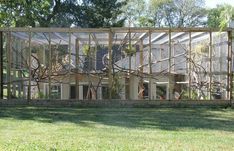 a house that is in the middle of some grass with trees on it and windows