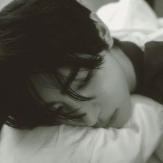 black and white photograph of a young woman sleeping on a bed with her head resting on the pillow