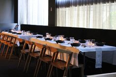 a long table is set up with empty glasses and plates on it in front of the window