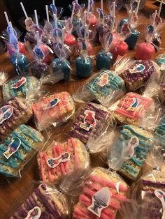 there are many decorated cookies in plastic bags on the table with candy sticks sticking out of them